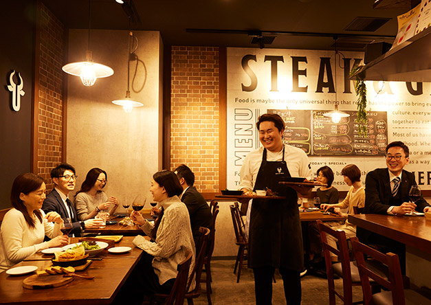 店員さんが笑顔でお料理を運ぶ